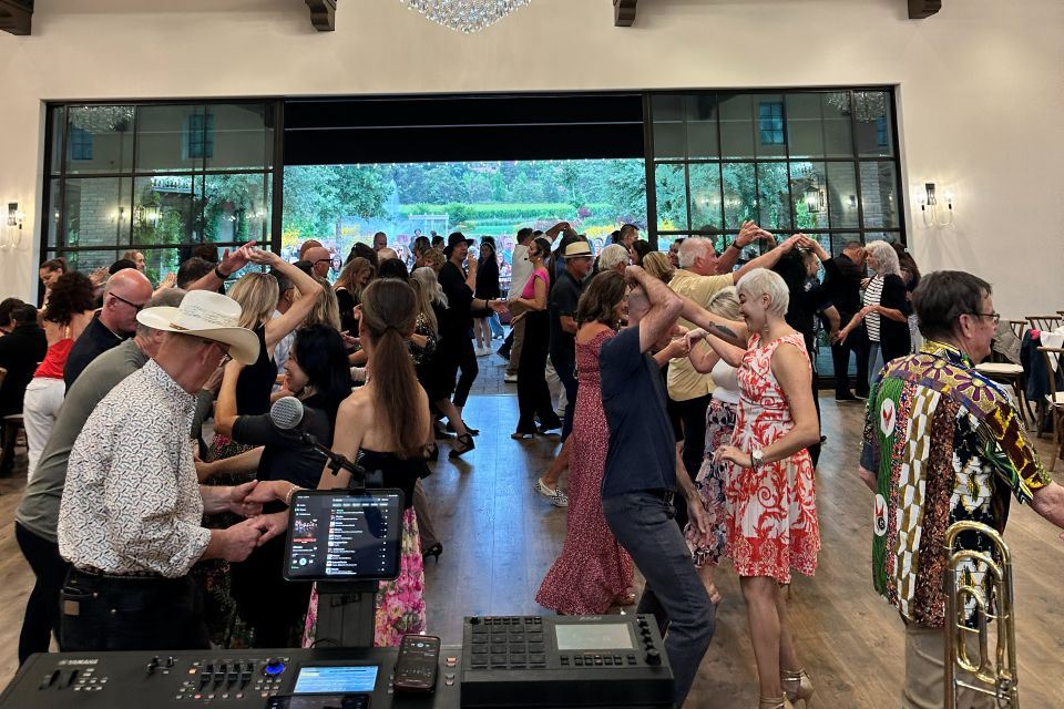 A packed floor of partner dancers under chandeliers at a large event